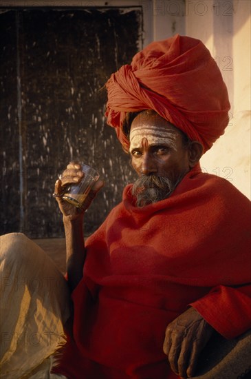 INDIA, Uttar Pradesh, Varanasi, Sadhu Holy man holding morning Chai