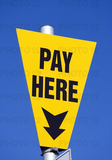 ENGLAND, West Sussex, Littlehampton, Yellow car park sign against a blue sky with black writing saying Pay Here
