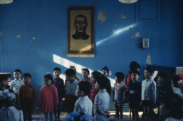 MONGOLIA, Education, Bigersum negdel  primary school  children singing to piano accompaniment with picture of first President Sukhebator on wall