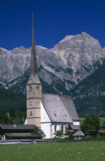 AUSTRIA, Salzburg, Maria Alm am Steinernen Meer, "Parish church exterior with long, narrow spire with Hochkonig mountain range behind.  Near Saalfelden."