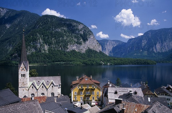 AUSTRIA, Oberosterreich, Hallstatt, "View over tiled village rooftops, hotel and church with lake and mountains behind."