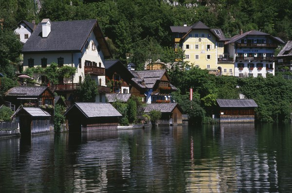 AUSTRIA, Oberosterreich, Hallstatt, Typical architecture and boat houses on shore of Hallstattersee Lake and reflected in rippled surface.