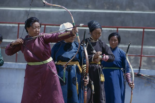 MONGOLIA, Ulan Bator, Ulan Bator Stadium on Nadam  National Day. Women taking part in national archery competition in traditional silk tunics. Ulaanbaatar East Asia Asian Baator Female Woman Girl Lady Mongol Uls Mongolian Ulaan