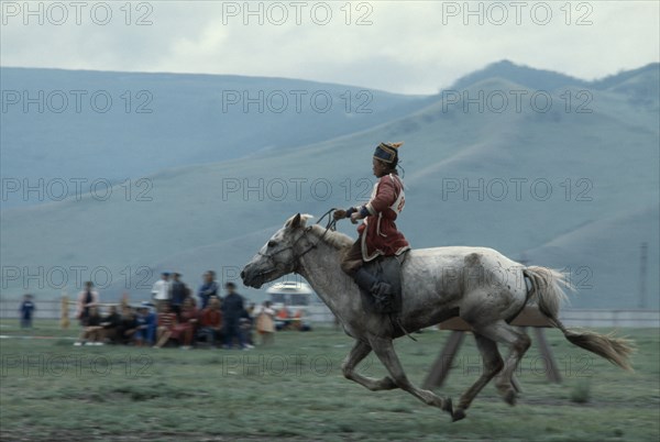 MONGOLIA, Ulan Bator, "Nadam  National Day  Child jockey coming to end of 20 mile cross country horse race, all jockeys must be under 12 years old    child will weigh less and not overstretch the horse. Ulaan Baatar East Asia Asian Baator Children Equestrian Mongol Uls Mongolian "