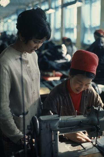 MONGOLIA, Work, Woman working at sewing machine in Ulan Bator tannery  leather factory with a young supervisor overseeing her work. East Asia Asian Female Women Girl Lady Mongol Uls Mongolian