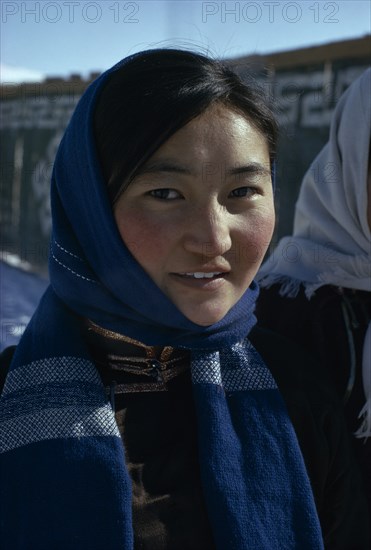 MONGOLIA, People, Altai provincial capital in winter. Head and shoulders portrait of young woman wearing fleece lined traditional tunic and modern woollen blue headscarf. East Asia Asian Female Women Girl Lady Mongol Uls Mongolian