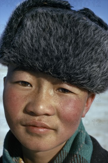 MONGOLIA, Children, Altai provincial capital. Portrait of young boy with typical fur hat with ear flaps against bitter winter cold.