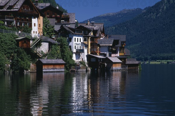 AUSTRIA, Oberosterreich, Hallstatt, Typical architecture and boat houses on shore of Hallstattersee Lake and reflected in rippled surface.