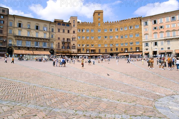 ITALY, Tuscany, Siena, People walking in the Piazza del Campo past the Palazzi and restaurants that border the square