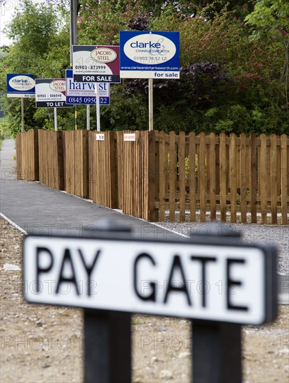 ENGLAND, West Sussex, Washington, To Let and For Sale signs on wooden fencing outside a newly built housing development in a road called Pay Gate