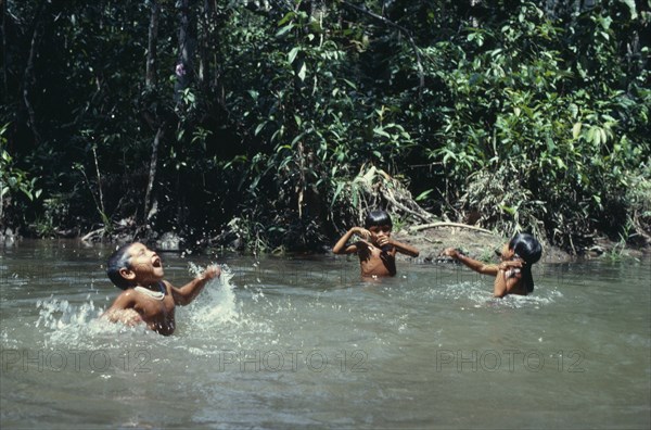COLOMBIA, North West Amazon, Tukano Indigenous People, Three young Makuna children playing in water at the maloca's river port. Tukano Indian North Western Amazonia American Colombian Columbia Hispanic Indegent Kids Latin America Latino South America Tukano