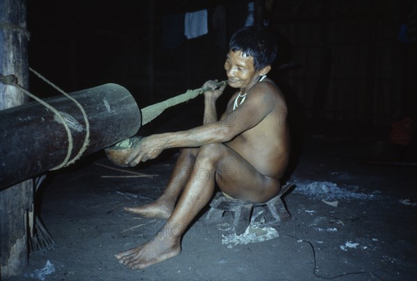 COLOMBIA, North West Amazon, Tukano Indigenous People, "Visiting Maku nomadic hunter pounding coca leaves to very fine powder  pours powder into a gourd, mixes with yarumo ash and puts into mouth. Maku nomadic hunter Indian North Western Amazonia Vaupes "