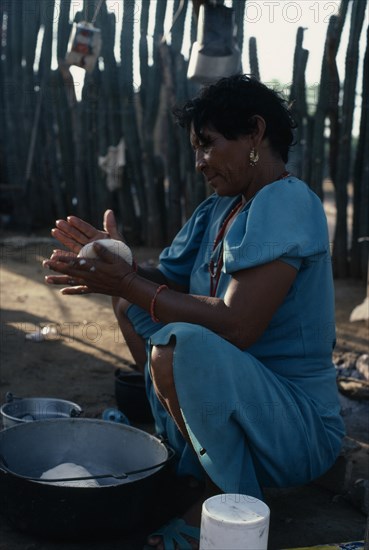 COLOMBIA, Guajira Peninsula, Guajiro Indians, "Guajira Indian woman in the process of making ""arepas"" from kneeded maize flour dough, over a fire in typical open shelter desert home. Wayu Wayuu Guajiro Amerindian Arawakan Colombia-Venezuela border American Colombian Columbia Female Women Girl Lady Hispanic Latin America Latino South America "