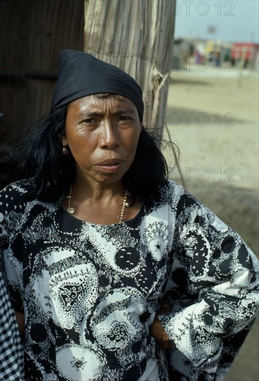 VENEZUELA, Guajira Peninsula, Guajiro Indians, Guajira Indian woman standing in typical manta guajira at entrance to open slatted desert home. Wayu Wayuu Guajiro Amerindian Arawakan Colombia-Venezuela border American Colombian Columbia Female Women Girl Lady H