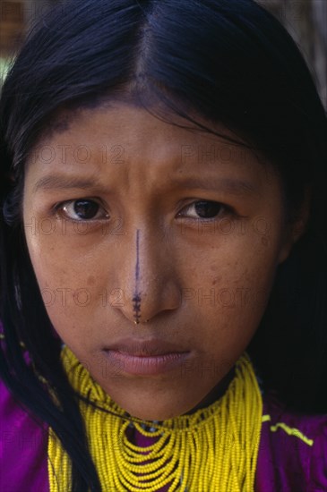 COLOMBIA, Darien, Kuna Indians, Head and shoulders portrait of Kuna girl from the Arquia community wearing gold nose ring  multi stranded necklace of yellow beads and traditional facial decoration consisting of painted black stripe running the length of the nose.  Cuna American Classic Classical Colombian Columbia Hispanic Historical Latin America Latino Older South America