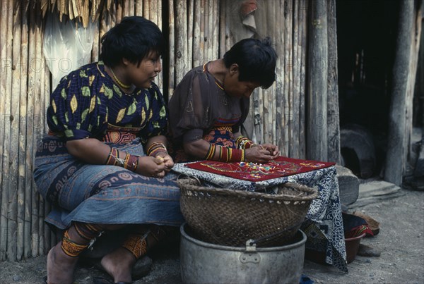 PANAMA, San Blas Islands, Kuna Indians, Kuna Indian women sewing together different layers of cut out cotton cloth to make molas for tourist market. Molas are brightly coloured cut-out traditional Kuna designs incorporated in layers as a front panel on a woman's normal dress. Cuna Caribbean American Central America Classic Classical Colored Female Women Girl Lady Hispanic Historical Latin America Latino Older Panamanian West Indies