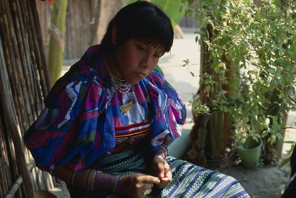 PANAMA, San Blas Islands, Kuna Indians, Kuna Indian girl wearing brightly coloured blouse or dulemola with applique layered mola panel  bead wrist and arm bands and nose ring with black stripe running length of nose. Cuna Caribbean American Central America Colored Hispanic Latin America Latino Panamanian West Indies