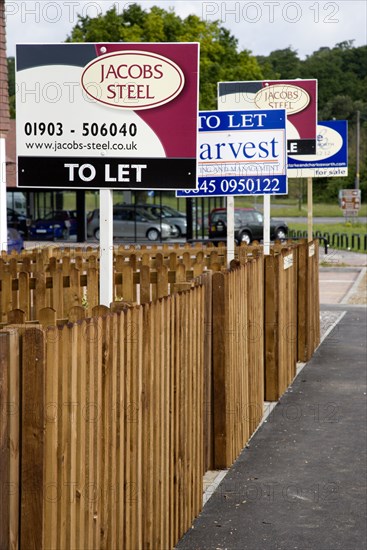 ENGLAND, West Sussex, Washington, To Let signs on wooden fencing outside a newly built housing development