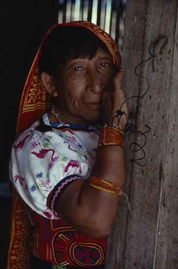 PANAMA, San Blas Islands, Kuna Indians, "Portrait of older Kuna Indian woman wearing traditional blouse or dulemola with brightly coloured multi-layered mola panel   bead arm and wrist bands, long head scarf against strong sun  and gold nose ring. Cuna Caribbean American Central America Classic Classical Colored Female Women Girl Lady Hispanic Historical Latin America Latino Older Panamanian West Indies "