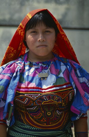 PANAMA, San Blas Islands Tikantiki , Kuna Indians, Portrail of Kuna girl wearing fine traditional layered applique mola   gold nose ring and bead wrist and arm bands with black line drawn along length of nose. Cuna Caribbean