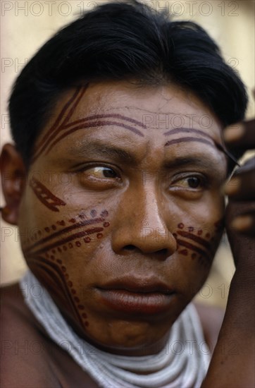 COLOMBIA, North West Amazon, Tukano Indigenous People, Barasana man applying dark red Achiote facial paint.  Tukano sedentary Indian tribe North Western Amazonia body decoration American Colombian Columbia Hispanic Indegent Latin America Latino Male Men Guy South America Tukano