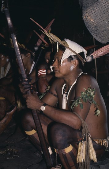 COLOMBIA, North West Amazon, Tukano Indigenous People, Barasana shaman  Pacico clutches sacred hardwood prayer stave during chanting session. He wears woven monkey fur amulets  woven cumare fibre garters on legs and sweet-smelling herbs on arms plus macaw toucan feather crown  Tukano sedentary Indian tribe North Western Amazonia American Colombian Columbia Hispanic Indegent Latin America Latino Religion South America Tukano One individual Solo Lone