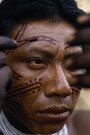 COLOMBIA, North West Amazon, Tukano Indigenous People, Barasana man applying red Achiote facial paint.  Tukano sedentary Indian tribe North Western Amazonia body decoration American Colombian Columbia Hispanic Indegent Latin America Latino Male Men Guy South America Tukano