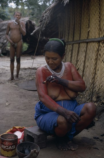 COLOMBIA, North West Amazon, Tukano Indigenous People, Barasana woman Paulina  applying red Achiote fruit body paint to arms and upper body in preparation for manioc festival.  Hands already coloured dark purple to wrists with we dye from boiled leaves.  Tukano sedentary Indian tribe North Western Amazonia body decoration American Colombian Columbia Female Women Girl Lady Hispanic Indegent Latin America Latino South America Tukano