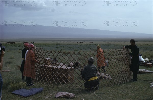 MONGOLIA, Gobi Desert, Khalkha herdsman's family erecting ger or yurt on summer grassland pasture for sheep grazing. First the wooden frame is erected.  Khalha East Asia Asian Mongol Uls Mongolian Scenic