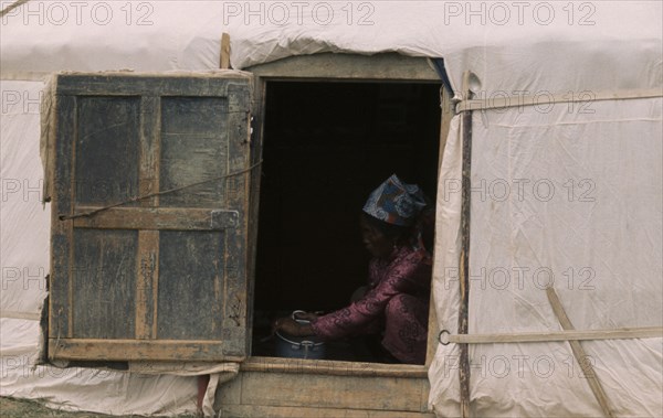 MONGOLIA, Gers Yurts, Khalkha Woman doing chores framed in open doorway of recently erected ger or yurt. East Asia Asian Female Women Girl Lady Mongol Uls Mongolian