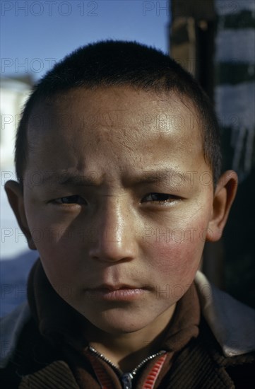 MONGOLIA, Altai town, Head and shoulders portrait of strong young Khalkha boy looking direct to camera. face on East Asia Asian Kids Mongol Uls Mongolian
