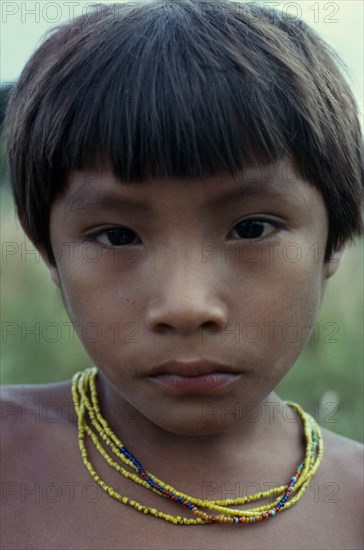 COLOMBIA, North West Amazon, Tukano Indigenous People, Head and shoulders portrait of young Barasana boy looking direct to camera  wearing multi-strand coloured bead necklace. Tukano sedentary Indian tribe North Western Amazonia