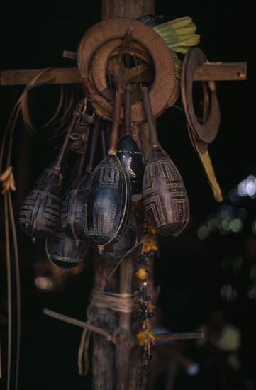 COLOMBIA, North West Amazon, Tukano Indigenous People, Makuna dancing regalia hanging from central house post engraved maracas  toucan feather crowns and nutshell rattles. Tukano Makuna Indian North Western Amazonia American Colombian Columbia Hispanic Indegent Latin America Latino Religion South America Tukano