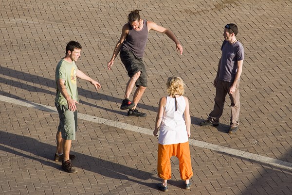 ENGLAND, East Sussex, Brighton, People playing keepy uppie with small red bean bag.