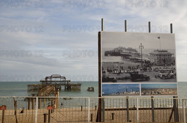 ENGLAND, East Sussex, Brighton, Ruins of the West pier with boards showing the pier in its former glory days.