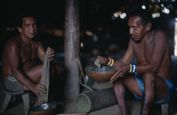 COLOMBIA, North West Amazon, Tukano Indigenous People, Makuna headman Ignacio taking powdered coca  refined and pounded through barkcloth bag.  Tukano  Makuna Indian North Western Amazonia American Colombian Columbia Hispanic Indegent Latin America Latino South America Tukano