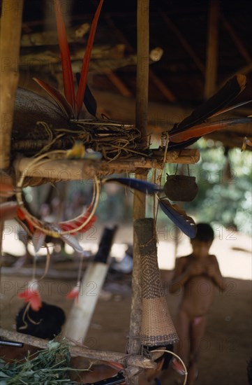 COLOMBIA, North West Amazon, Vaupes, Macaw feather ceremonial crowns and finely woven blow pipe dart quiver waterproofed with molten beeswax hang beside curare poison pot in base village  indigenous tribe indian nomadic American Colombian Columbia Hispanic Indegent Latin America Latino South America Vaupes