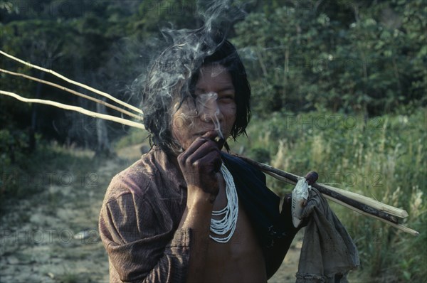 COLOMBIA, North West Amazon, Tukano Indigenous People, Barasana Indian smoking home grown tobacco and holding bar of Lux soap returns from fishing trip. Tukano sedentary Indian tribe North Western Amazonia  Western influence American Colombian Columbia Hispanic Indegent Inn Latin America Latino Pub South America Tavern Tukano One individual Solo Lone Solitary Public House