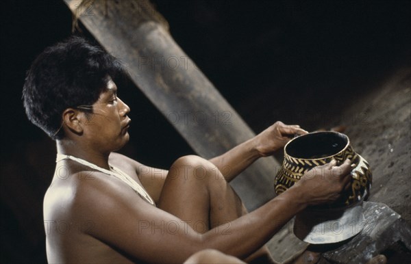 COLOMBIA, North West Amazon, Tukano Indigenous People, Barasana tribesman Pacico a shaman painting clay design onto yaje pot used to hold hallucinogenic yaje juice from vine species Banisteriopsis used for shamanic and religious purposes Tukano sedentary Indian tribe North Western Amazonia ayahuasca American Colombian Columbia Hispanic Indegent Latin America Latino Religion South America Tukano One individual Solo Lone Solitary