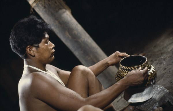 COLOMBIA, North West Amazon, Tukano Indigenous People, Barasana tribesman  Pacico  a shaman painting clay design onto yaje pot used to hold hallucinogenic yaje juice from vine species Banisteriopsis used for shamanic and religious purposes Tukano sedentary Indian tribe North Western Amazonia ayahuasca American Colombian Columbia Hispanic Indegent Latin America Latino Religion South America Tukano One individual Solo Lone Solitary