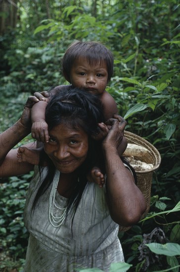 COLOMBIA, North West Amazon, Tukano Indigenous People, Makuna mother carrying baby on her shoulders and basket of scraped manioc roots on her back. Tukano  Makuna Indian North Western Amazonia family American Babies Colombian Columbia Hispanic Indegent Kids Latin America Latino Mum Scenic South America Tukano