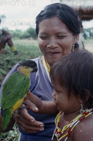 COLOMBIA, North West Amazon, Tukano Indigenous People, Makuna mother and child with pet parrot.  Both  wearing necklaces of white red and yellow beads. Tukano  Makuna Indian North Western Amazonia family American Children Colombian Columbia Hispanic Indegent Kids Latin America Latino Mum South America Tukano