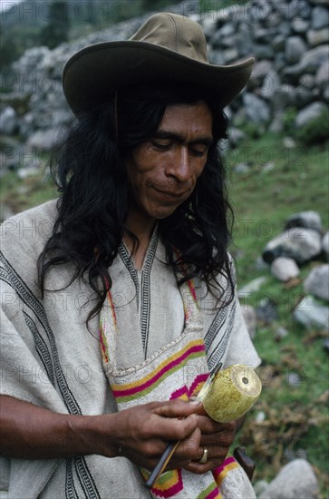 COLOMBIA, Sierra Nevada de Santa Marta, Ika, Ika man in traditional dress with hand woven mochila shoulder bag and holding poporo a small gourd containing finely powdered lime from burnt sea shells.He sticks the the lime into a wad of coca leaves held in the cheek.Lime acts as catalyst to release the cocaine alkaloid from the chewed leaves.  Arhuaco Aruaco indigenous tribe American Classic Classical Colombian Colombia Hispanic Historical Indegent Latin America Latino Male Men Guy Older South America  Arhuaco Aruaco indigenous tribe American Classic Classical Colombian Columbia Hispanic Historical Indegent Latin America Latino Male Men Guy Older South America History Male Man Guy One individual Solo Lone Solitary 1 Single unitary