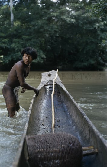 COLOMBIA, Choco, Embera Indigenous People, "Embera man, Rio Verde, standing knee deep in water beside his wooden dug out canoe. Pacific coastal region boat piragua tribe "