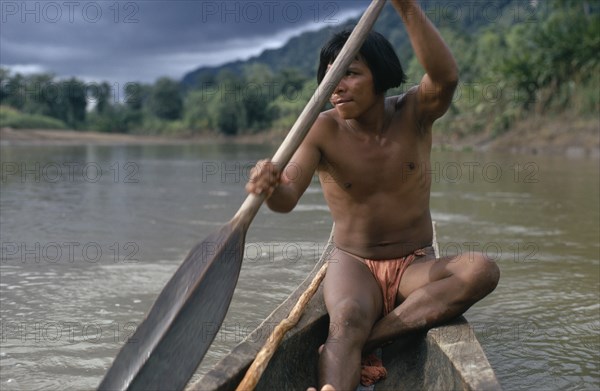 COLOMBIA, Choco, Embera Indigenous People, Embera man using single oar to steer wooden dug out canoe along rio Baudo. Pacific coastal region boat piragua tribe