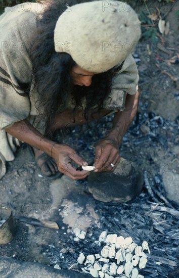 COLOMBIA, Sierra Nevada de Santa Marta, Ika, Ika man burning sea shells  brought into the Sierra from the Caribbean Coast  to make very fine powdered lime which is carried in a poporo small gourd  then inserted into a wad of coca leaves constantly held in the cheek. Lime acts as the catalyst to extract cocaine alkaloid from the coca leaves.  Arhuaco Aruaco indigenous tribe American Colombian Colombia Hispanic Indegent Latin America Latino Male Men Guy South America  Arhuaco Aruaco indigenous tribe American Colombian Columbia Hispanic Indegent Latin America Latino Male Men Guy South America Male Man Guy One individual Solo Lone Solitary 1 Single unitary West Indies