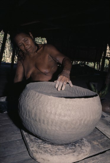 COLOMBIA, Choco, Embera Indigenous People, Embera woman puts final touches to a large clay cooking pot. Fashioning the poit with her fingers she smoothens the surface with a smooth river-worn pebble  Skill is only continued by a few elderly women. Pacific coastal region tribe vessel American Colombian Colombia Female Woman Girl Lady Female Women Girl Lady Hispanic Indegent Latin America Latino Old Senior Aged South America  Pacific coastal region tribe vessel American Colombian Columbia Female Woman Girl Lady Female Women Girl Lady Hispanic Indegent Latin America Latino Old Senior Aged South America One individual Solo Lone Solitary 1 Single unitary