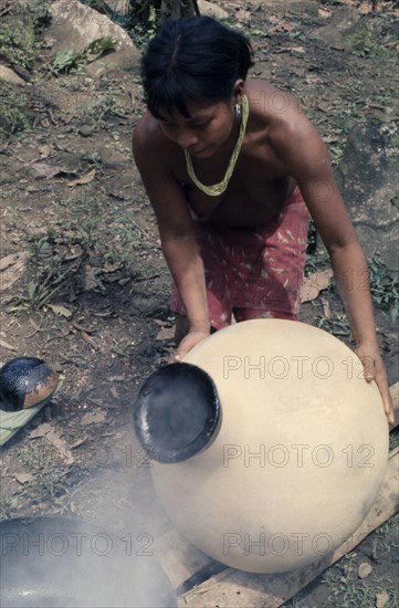 COLOMBIA, Choco, Embera Indigenous People, "Embera woman uses molten beeswax to seal a  cantaro  water-container/pot to make it completely watertight, after firing the pot at the riverside. Pacific coastal region tribe vessel American Colombian Colombia Female Women Girl Lady Hispanic Indegent Latin America Latino South America  Pacific coastal region tribe vessel American Colombian Columbia Female Women Girl Lady Hispanic Indegent Latin America Latino South America Female Woman Girl Lady One individual Solo Lone Solitary 1 Single unitary "