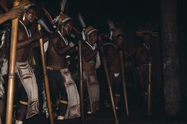 COLOMBIA, North West Amazon, Tukano Indigenous People, "Barasana stave dance  hollow yarumo wood staves rhythmically pounded on ground  Line of male dancers wear painted barkcloth aprons and ceremonial royal crane,toucan & macaw feather head-dresses, their faces painted with red Achiote fruit dye. Tukano sedentary Indian tribe North Western Amazonia American Colombian Columbia Hispanic Indegent Latin America Latino Performance South America Tukano   "