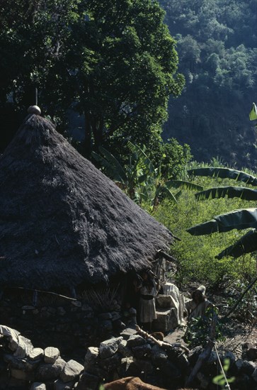 COLOMBIA, Sierra Nevada de Santa Marta, Ika, Ika man woman and child outside circular mud-wattle kankurua temple  grass-thatched conical roof with sacred religious pots at apex. In background old stone terraces. Arhuaco Aruaco indigenous tribe American Children Colombian Colombia Female Women Girl Lady Hispanic Indegent Kids Latin America Latino Male Men Guy South America  Arhuaco Aruaco indigenous tribe American Children Colombian Columbia Female Women Girl Lady Hispanic Indegent Kids Latin America Latino Male Men Guy South America Female Woman Girl Lady Male Man Guy Religion